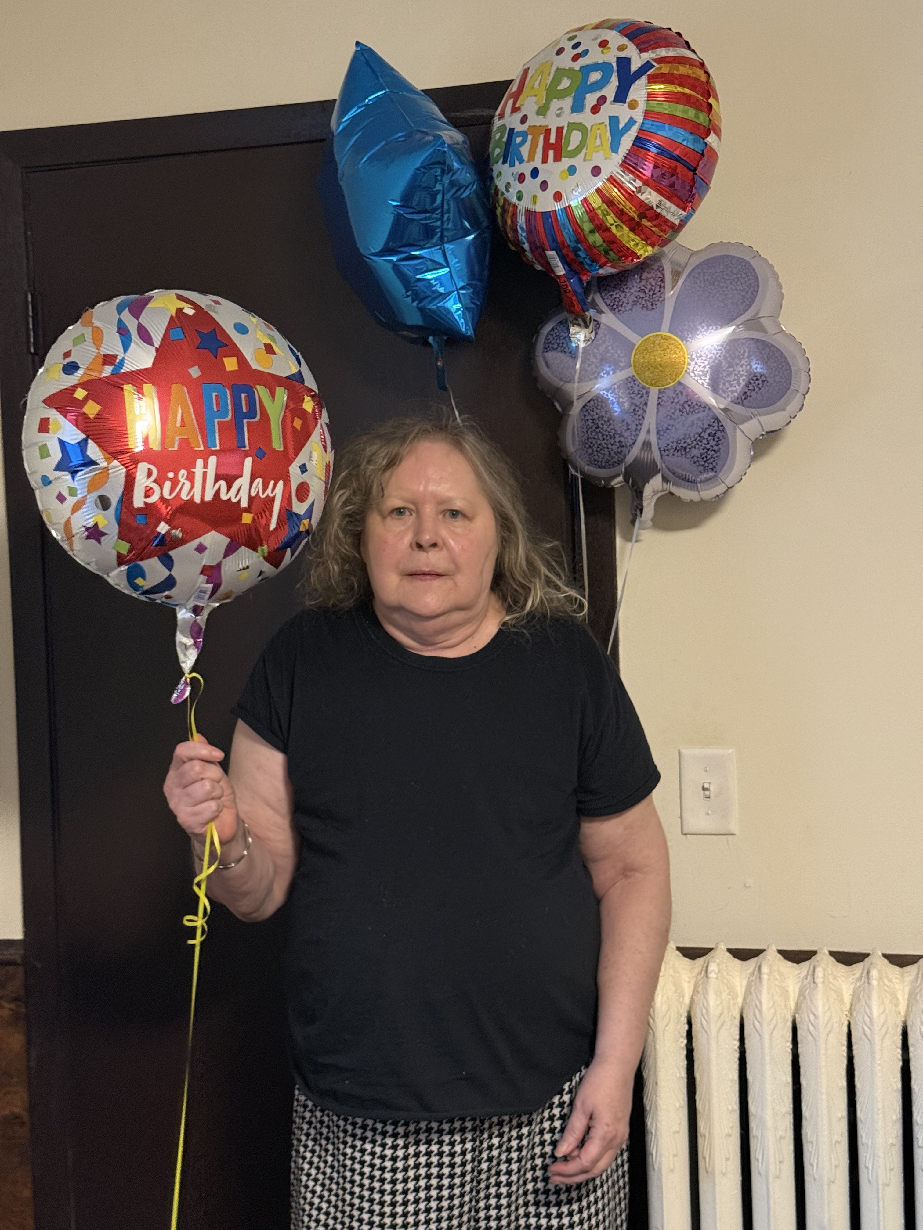 A resident holding a bunch of Happy Birthday balloons in the hallway